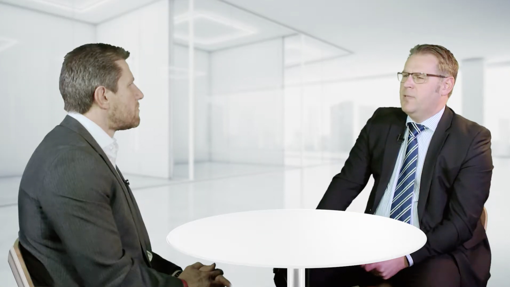 Two business men talking in a glass room