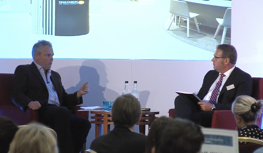 Two business men talking on a stage to an audience